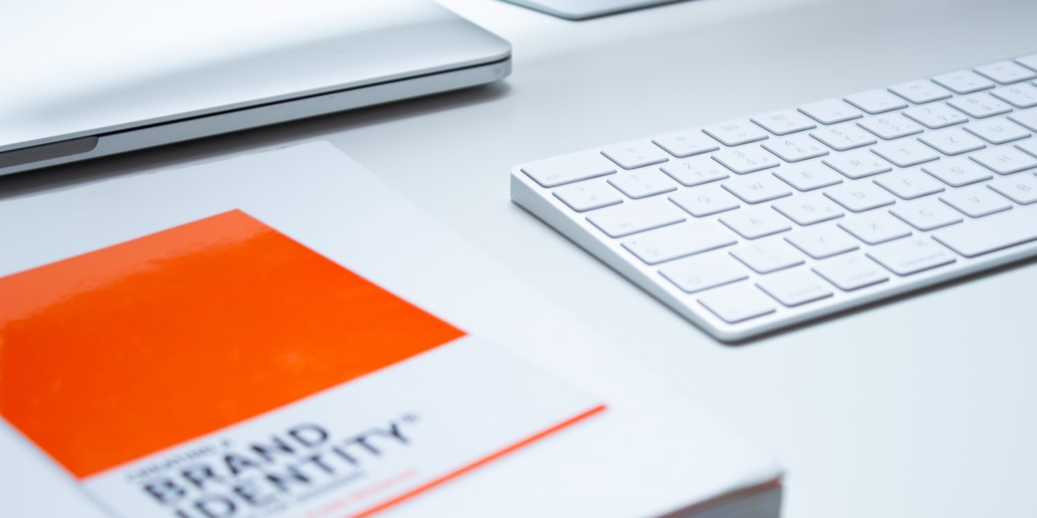 Part of the desk featuring a white keyboard and a brochure 