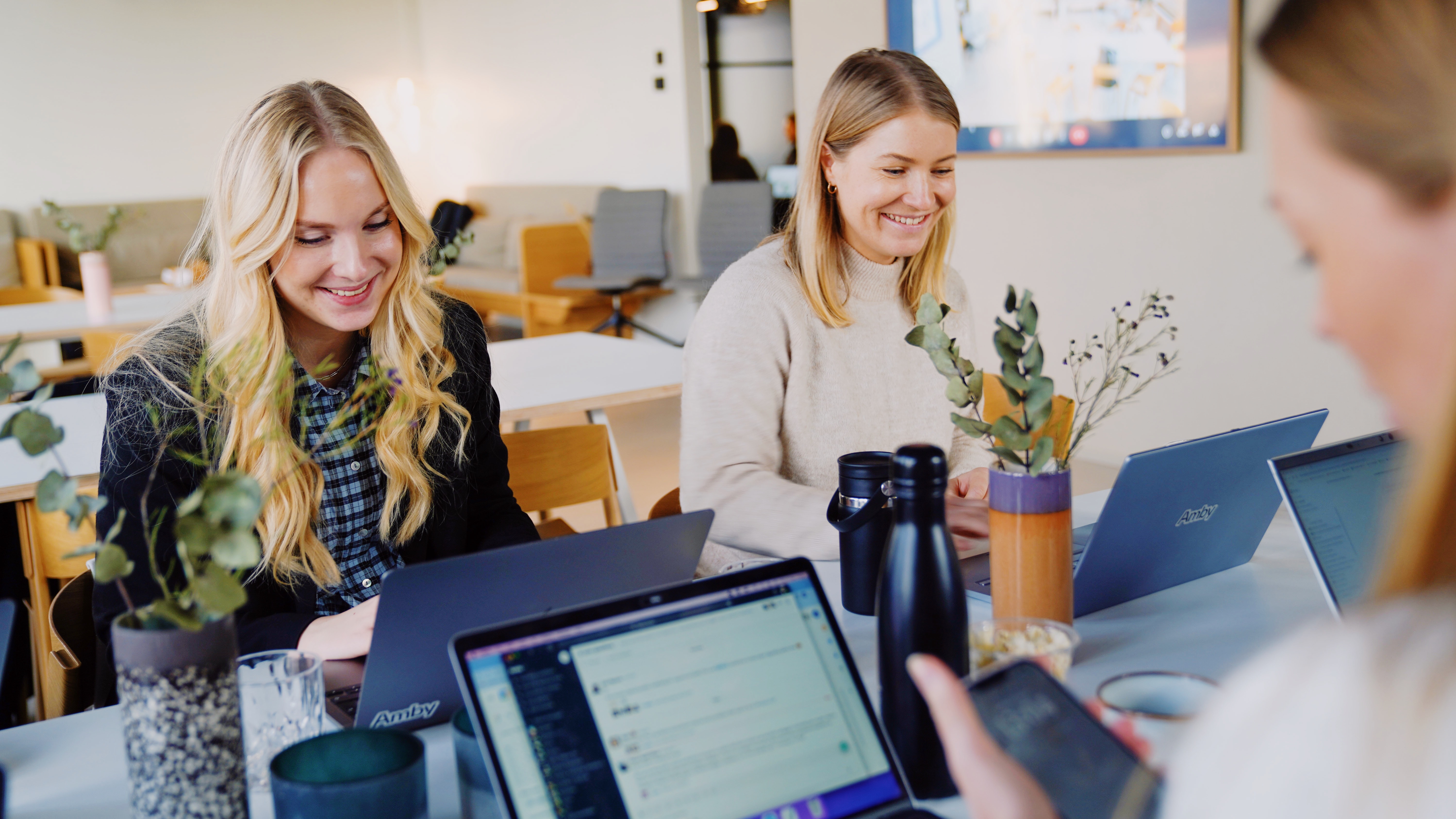 Two female team members smiling at the desk