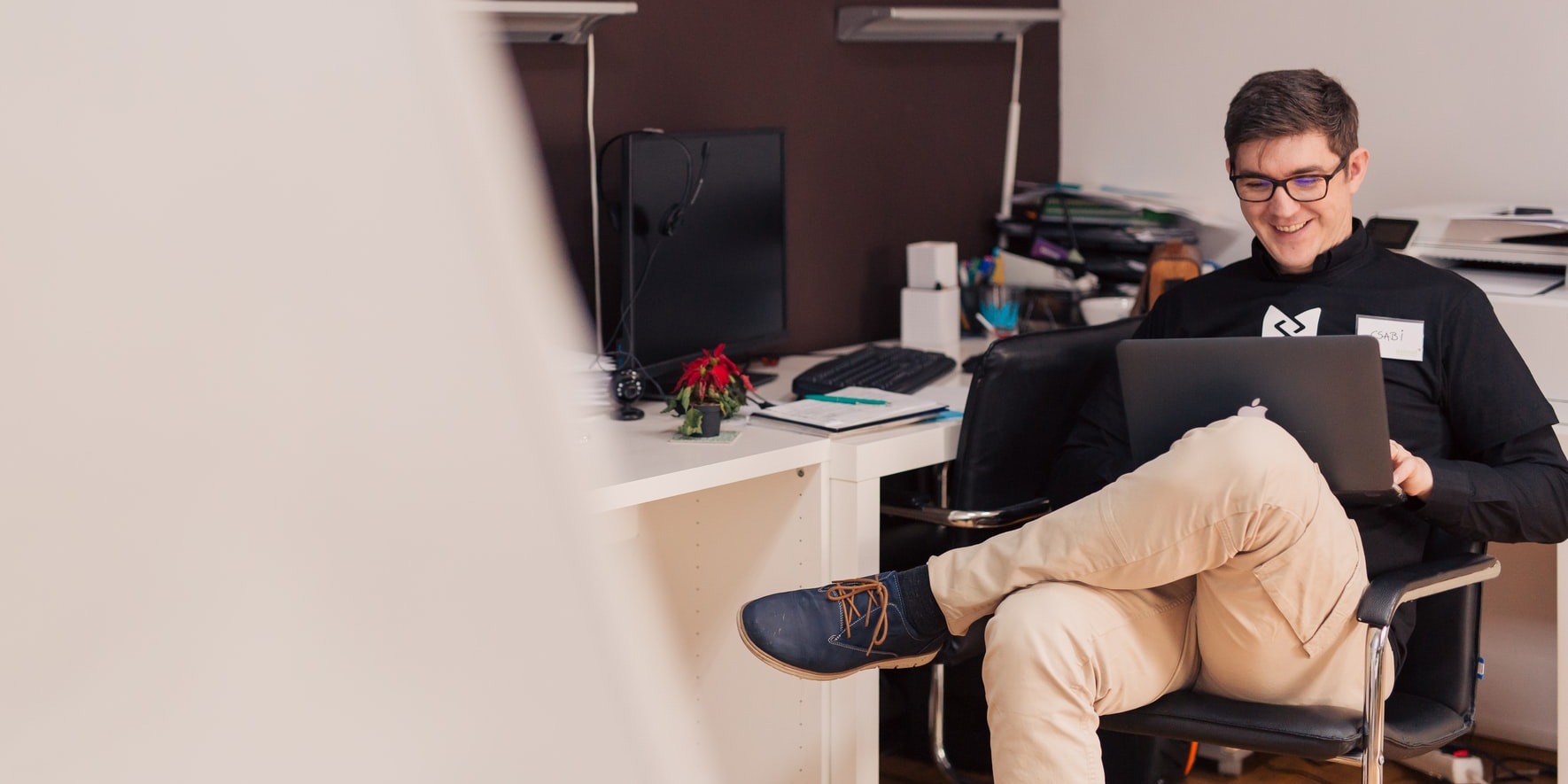 A young man sitting on a chair and looking into his laptop