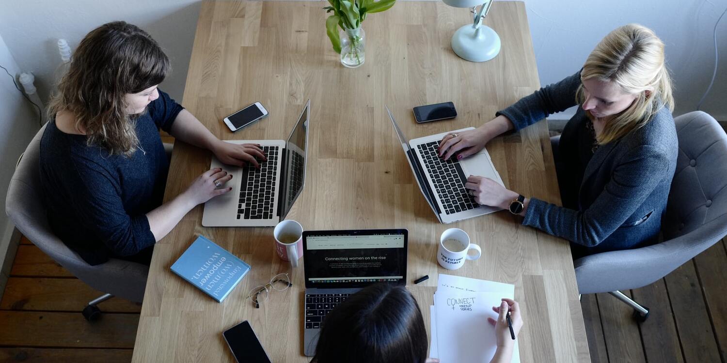 Three people at the desk on their laptops