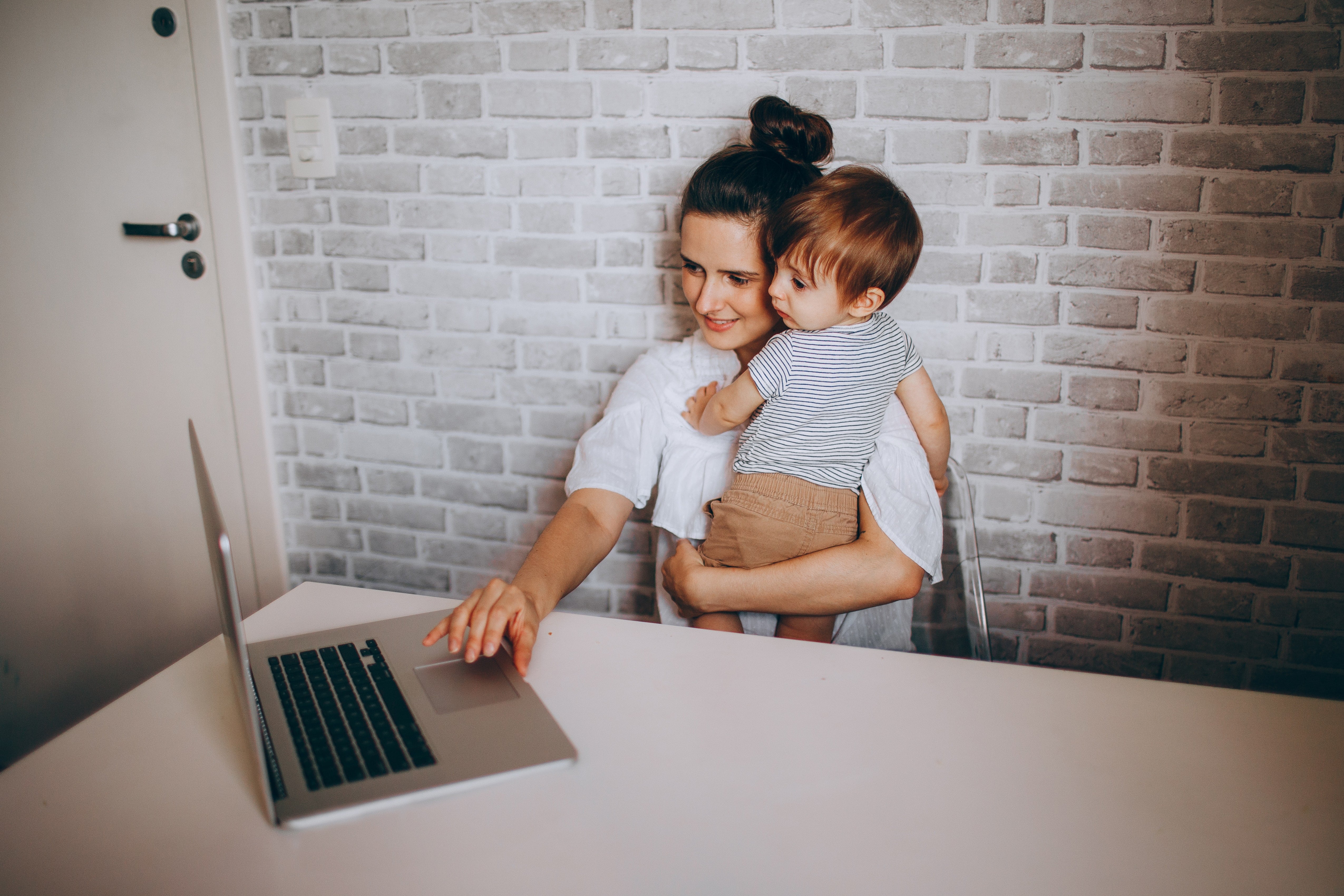Woman on computer while holding child