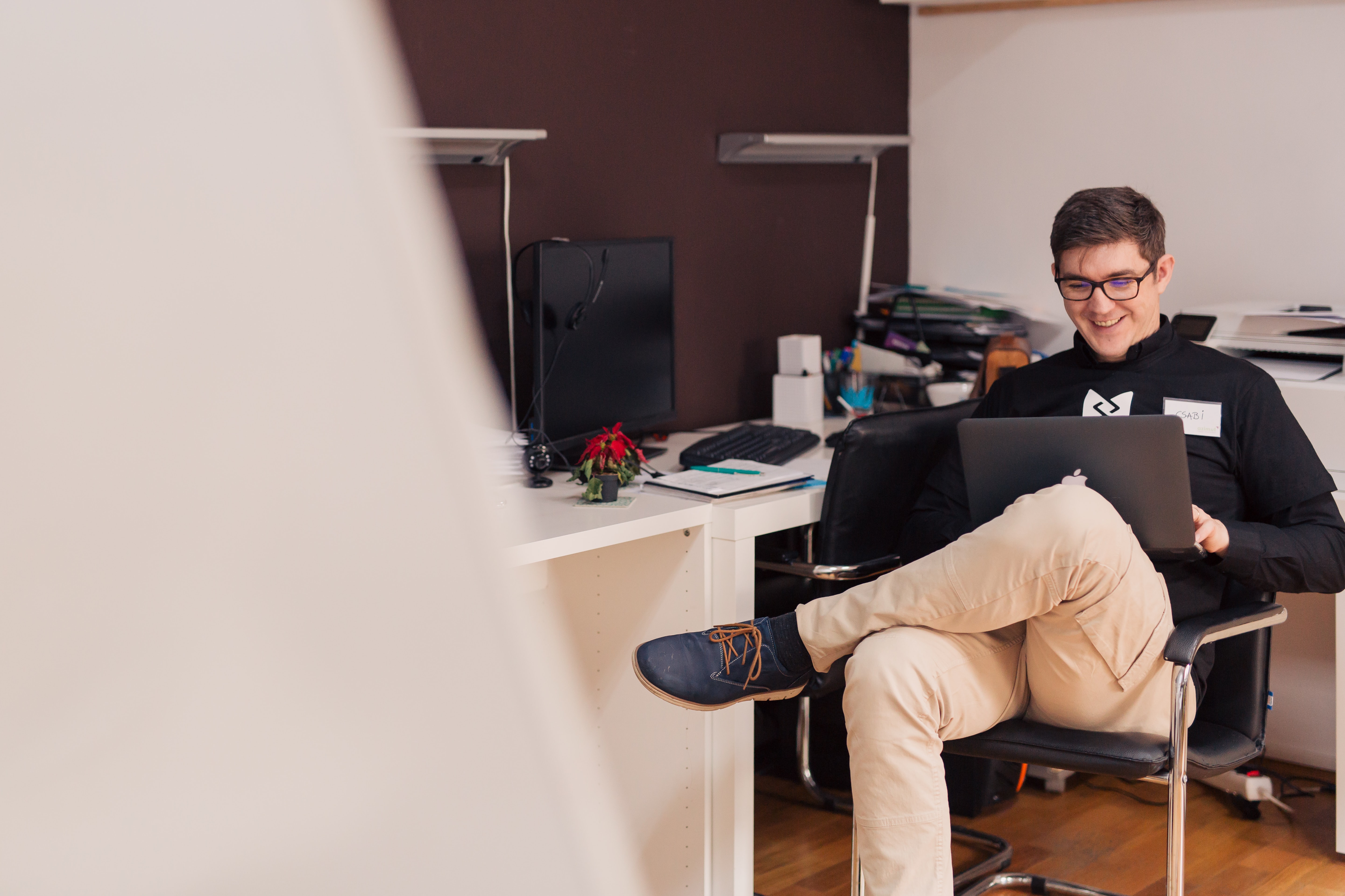 A young man in the office sitting on the chair with his laptop