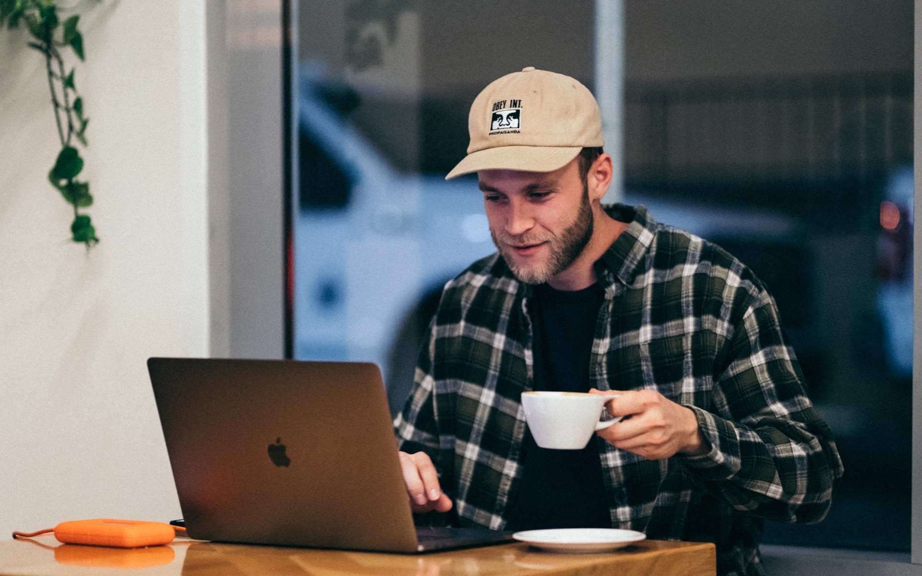 Man with a cup working on his laptop at the desk